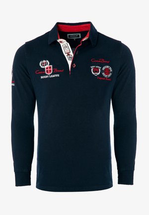 Mornarsko modra rugby polo majica z dolgimi rokavi in rdečimi poudarki, z gumbi na sprednji strani, izvezenimi logotipi in rebrastimi manšetami. Bombažna tkanina zagotavlja udobje.