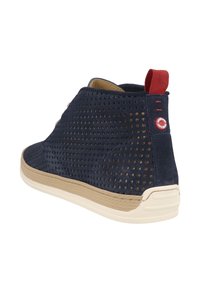 Stivali chukka in suede blu navy con texture perforata, suola in gomma color cuoio e linguetta rossa sul tallone. Presenta un dettaglio con logo rotondo sul tallone.
