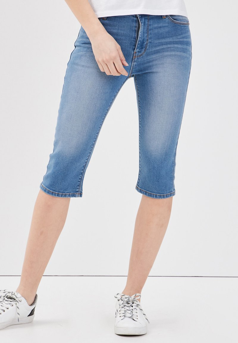 Shorts in denim blu chiaro, con vestibilità slim e orlo risvoltato. Indossati con sneakers bianche; dettagli di cucitura minimi.