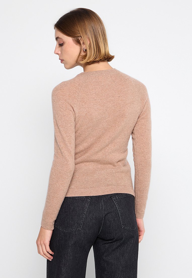 Helles beige Langarmshirt aus weichem Strickstoff mit rundem Ausschnitt sowie gerippten Manschetten und Saum. Schlicht, ohne Muster oder Verzierungen.
