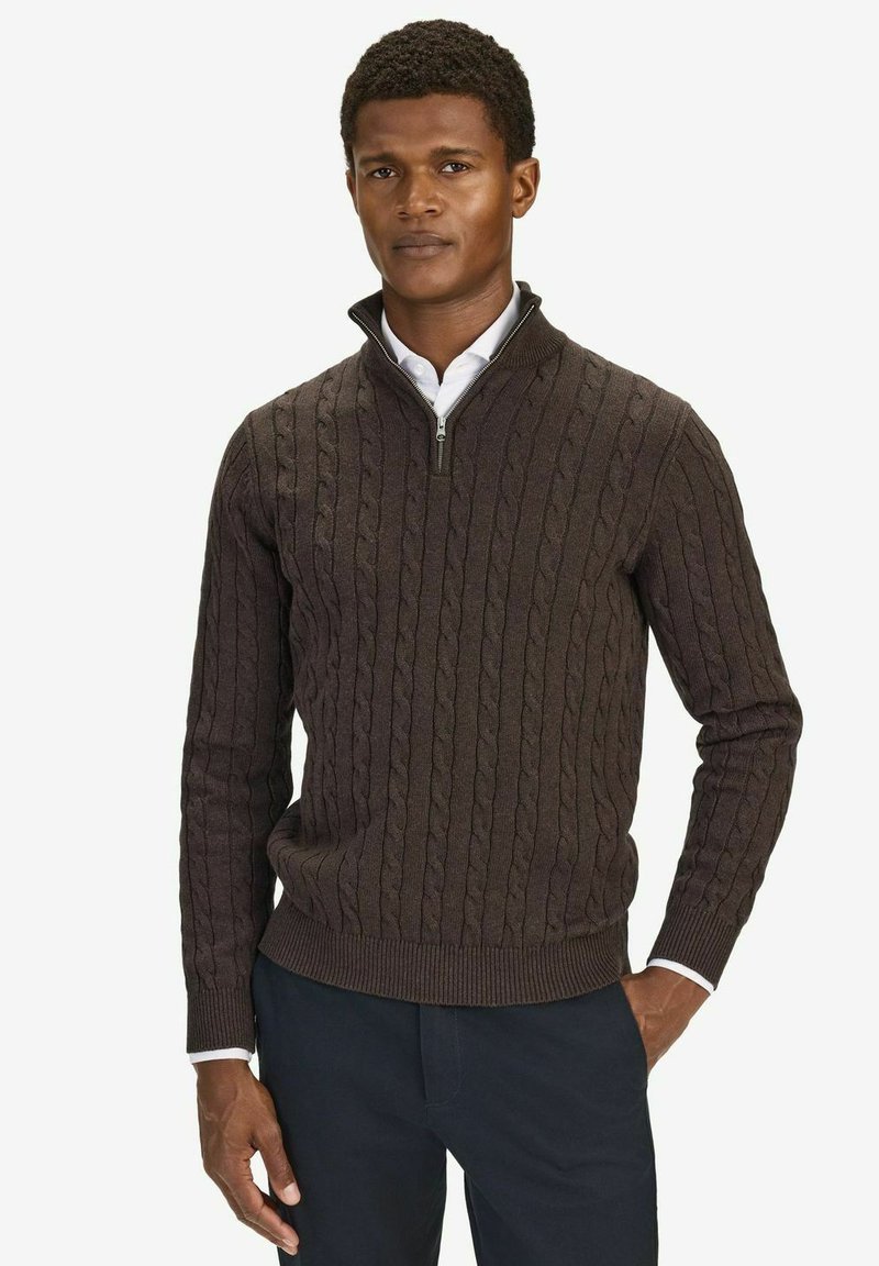 Mörkbrun kabelstickad tröja med hög krage och halvdragkedja. Materialet verkar mjukt och passformen är skräddarsydd, vilket framhäver texturen.