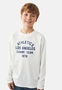 Biała koszulka z długim rękawem z granatowym napisem "ATHLETICS LOS ANGELES CHAMP. TEAM. 1978," wykonana z miękkiej bawełny.