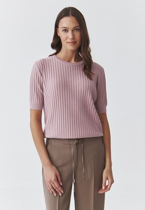 Top a coste rosa chiaro con maniche corte e scollo rotondo, abbinato a pantaloni beige con coulisse. Tessuto morbido e design attillato.