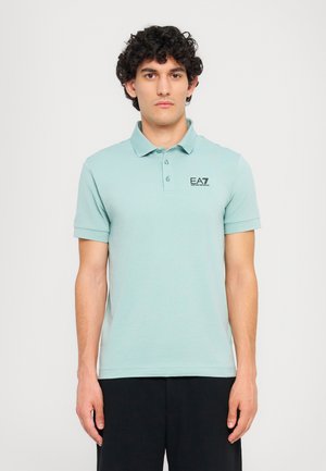 Lys blå kortermet polo skjorte med krage, med en svart EA7-logo på venstre bryst. Glatt stofftekstur og klassisk passform.