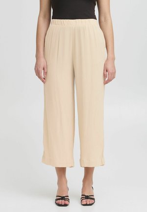 Beige wijde broek met een elastische tailleband, lichtgewicht textuur en subtiele plooien. De zoom eindigt op halverwege het kuit.