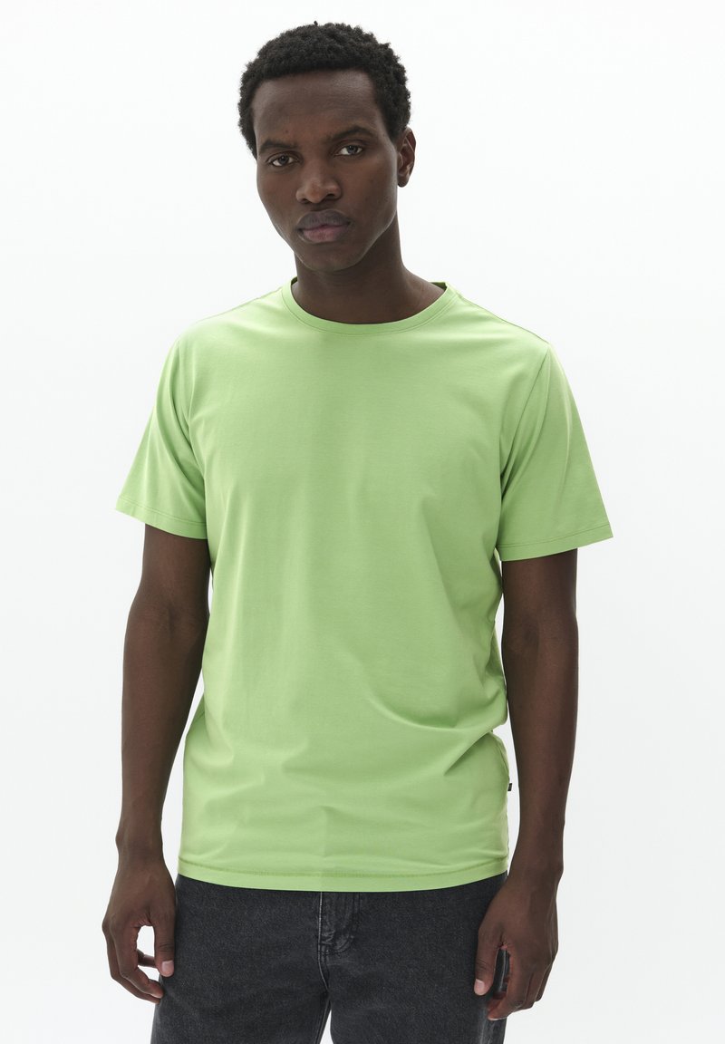 Camiseta de manga corta verde claro con cuello redondo, hecha de tela suave, con un diseño simple y sin patrones ni logotipos visibles.