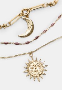 Guldtonade lagerhalsband med en böjd halvmånependant, en solpendant och maroonfärgade pärlaccenter på delikata kedjor.