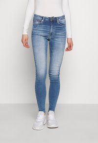 Jeans ajustados azules con un lavado desgastado, cinco bolsillos y un cierre de botón plateado. Presentan un ligero elastano y un acabado suave y limpio.