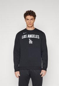 Melnas sporta džemperis, kas izgatavots no mīksta auduma, ar apaļu kaklu un garām piedurknēm. Uz krūtīm baltā krāsā ir izdrukāti vārdi "Los Angeles" un "LA".