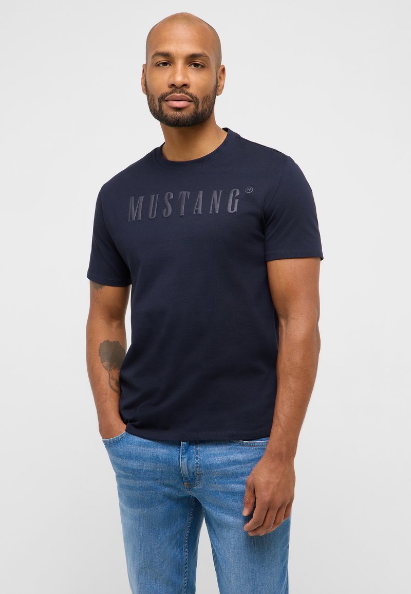 Navy blue short-sleeved t-shirt made of cotton, featuring a prominent light gray "MUSTANG" logo across the chest.