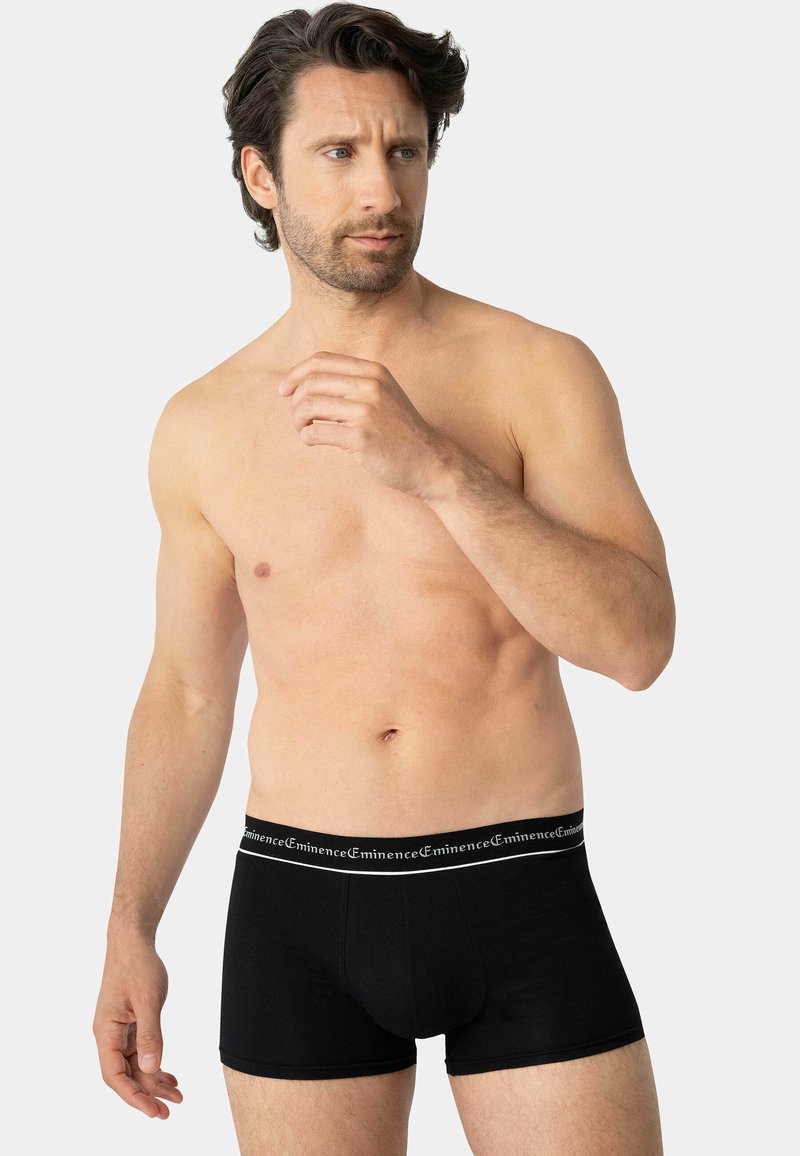 Boxers en coton noirs au style ajusté, avec une ceinture de marque contrastante. Texture lisse et design minimaliste.