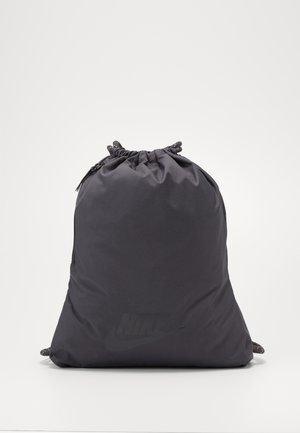 Sac à dos noir à cordon avec un logo Nike discret, serré en haut, sur un fond clair uni.