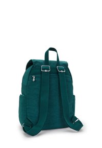 Mochila de tela en color azul verdoso con correas ajustables, dos bolsillos laterales, herrajes plateados y superficie texturizada. Cuenta con un asa superior y un compartimento principal con cremallera.