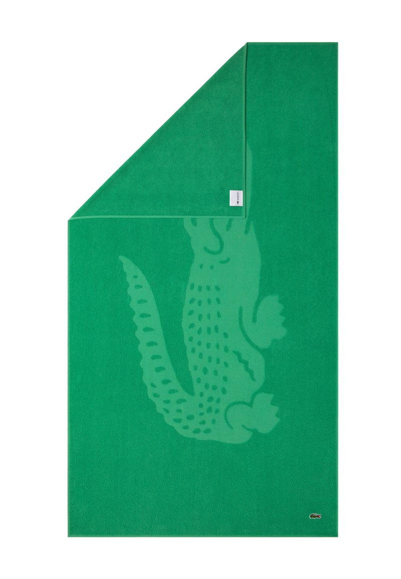 Toalla de algodón verde con un sutil diseño de cocodrilo. Presenta una etiqueta tejida y una superficie suave y texturizada. Esquinas bien dobladas.