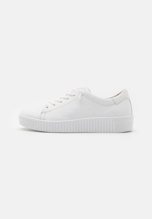 Białe sneakersy z gładką skórzaną cholewką, zaokrąglonym noskiem, sześcioma otworami na sznurowadła oraz teksturowaną gumową podeszwą z pionowymi rowkami.
