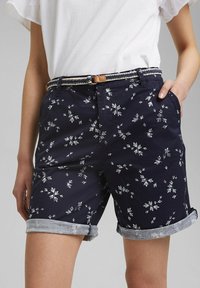 Námořnické květinové šortky s bílými květinovými vzory, srolované manžety a tkaným opaskem. Vyrobené z lehké bavlněné tkaniny, s bočními kapsami.