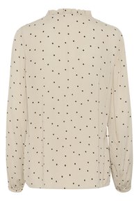 Beige long-sleeve blouse with black polka dots, featuring a ruffled neckline and elasticized cuffs, made of lightweight fabric.