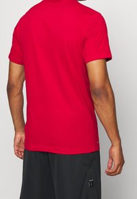 Rode katoenen T-shirt met ronde hals en korte mouwen. Heeft een soepele textuur en een discreet merklogo nabij de zoom.