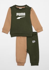 Chándal para toddlers en verde y marrón con un logo en el pecho, mangas largas y pantalones a juego con un parche de logo lateral. Tejido suave.