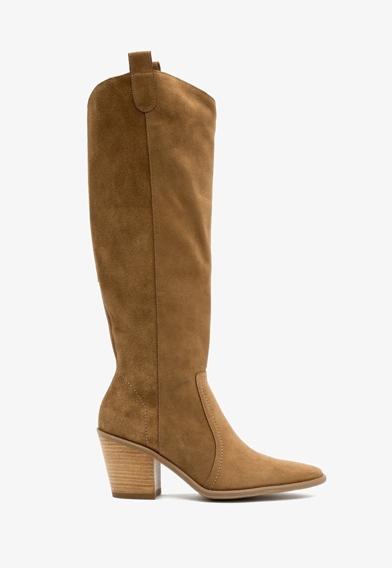 Botte hauteur genou en daim beige avec bout pointu, talon empilé et tige effilée. Présente une texture lisse et des détails de coutures simples.