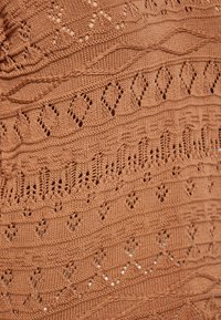 Maglione in arancio ruggine caratterizzato da texture diverse, motivi a diamante e a cuore, e delicate rifiniture di pizzo in tutto il tessuto.