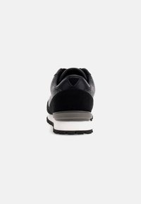 Sneaker nera e grigia con tomaia in tessuto e dettagli in pelle scamosciata, dotata di una suola in gomma resistente e di un colletto imbottito per il comfort.
