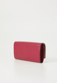 Portefeuille en cuir fuchsia avec une finition texturée, de forme rectangulaire élégante, et un rabat ouvert révélant un intérieur lisse.