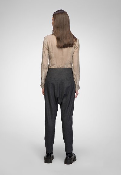 Light beige, sheer button-up shirt paired with dark gray, loose-fitting trousers. Trousers feature back pockets and a tapered shape. Black boots.
