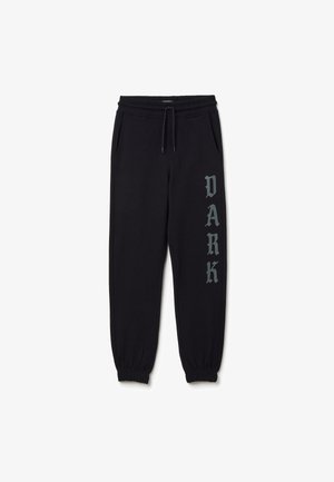 Zwarte joggingbroek van zacht materiaal, met een trekkoord in de taille, zijzakken en het woord "DARK" in vette grijze letters.