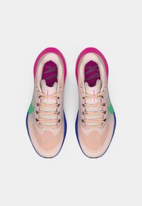 Skriešanas apavi ar sieta augšdaļu gaisīgi rozā krāsā, zaļš Nike zīmogs, rozā akcenti apkaklītē un zila gumijas zole. Šņores košā rozā krāsā.