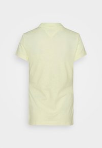 Polo en jaune clair, à manches courtes, col classique, texture lisse, design discret et sans logos ni graphiques visibles.