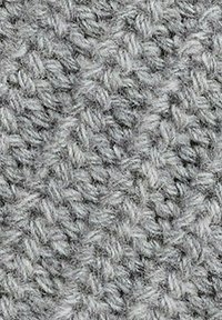 Szara dzianina o fakturowanym wzorze z pętelkami, tworząca miękki, masywny wygląd. Włókna są grube i puszyste.