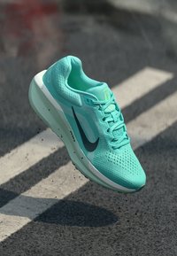 Teal running shoe with mesh upper, cushioned sole, and black Nike swoosh. Features flat laces and textured material for breathability.