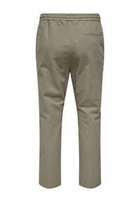 Khaki bukser med elastisk talje, behårede ender og en enkelt baglomme. Stoffet fremstår glat med en subtil tekstur.