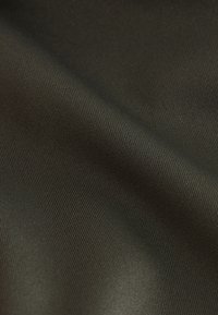 Donkergroen textiel met een zachte structuur, een glad oppervlak en een subtiel geribbeld patroon dat het licht zachtjes over het materiaal weerkaatst.