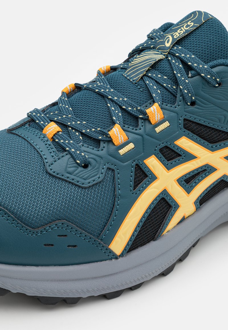 Baskets de course Asics bleu et jaune avec un tissu en maille, un bout renforcé, des lacets à motifs et une semelle texturée grise, vue en angle.