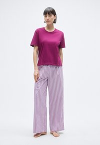 T-shirt à manches courtes magenta associé à un pantalon large à rayures violet clair. Matière en coton, coupe décontractée, texture lisse.