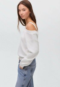 Vit off-shoulder-tröja med ribbad mudd, parat med ljusblå högmidjade jeans med en avslappnad passform och texturerad stickning.