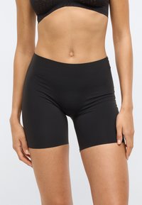 Μαύρο ψηλόμεσο σορτς από λείο, ελαστικό ύφασμα. Μήκος μέχρι το μέσο του μηρού με εφαρμοστή σιλουέτα και χωρίς ορατές ραφές.