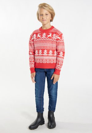 Roter gestrickter Pullover mit weißen Rentier- und Schneeflockenmustern, runder Ausschnitt, gerippte Bündchen, kombiniert mit blauen Jeans und schwarzen Knöchelstiefeln.