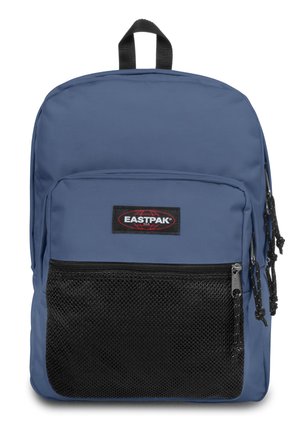 Mochila azul con un bolsillo frontal de malla negra, cierre con cremallera y un asa en la parte superior. Presenta un parche de logo en rojo y negro. Material duradero.