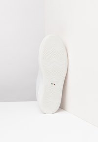 Baskets blanches avec une semelle en caoutchouc texturée à motif en zigzag et logo imprimé. Tige en matériau lisse avec accents minimalistes. Taille 37.