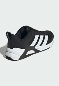 Black athletic shoe with white stripes, textured upper, padded collar, and a sturdy rubber sole featuring a triangular accent for support.