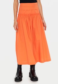 Lång orange bomullsskjorta med en tärningsdesign, samlad midja och en slät textur; i kombination med svarta ankelstövlar.