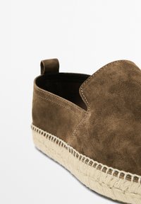 Brune ruskinds slip-on sko med rund tå, jute reb ydersål og syningsdetaljer langs kanten. Har en lille hælflap bagpå.