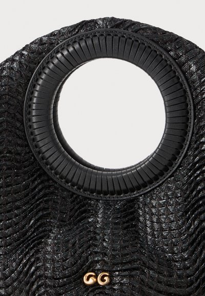 Black woven handbag featuring a circular, textured handle. Includes gold hardware with two circular accents at the base.