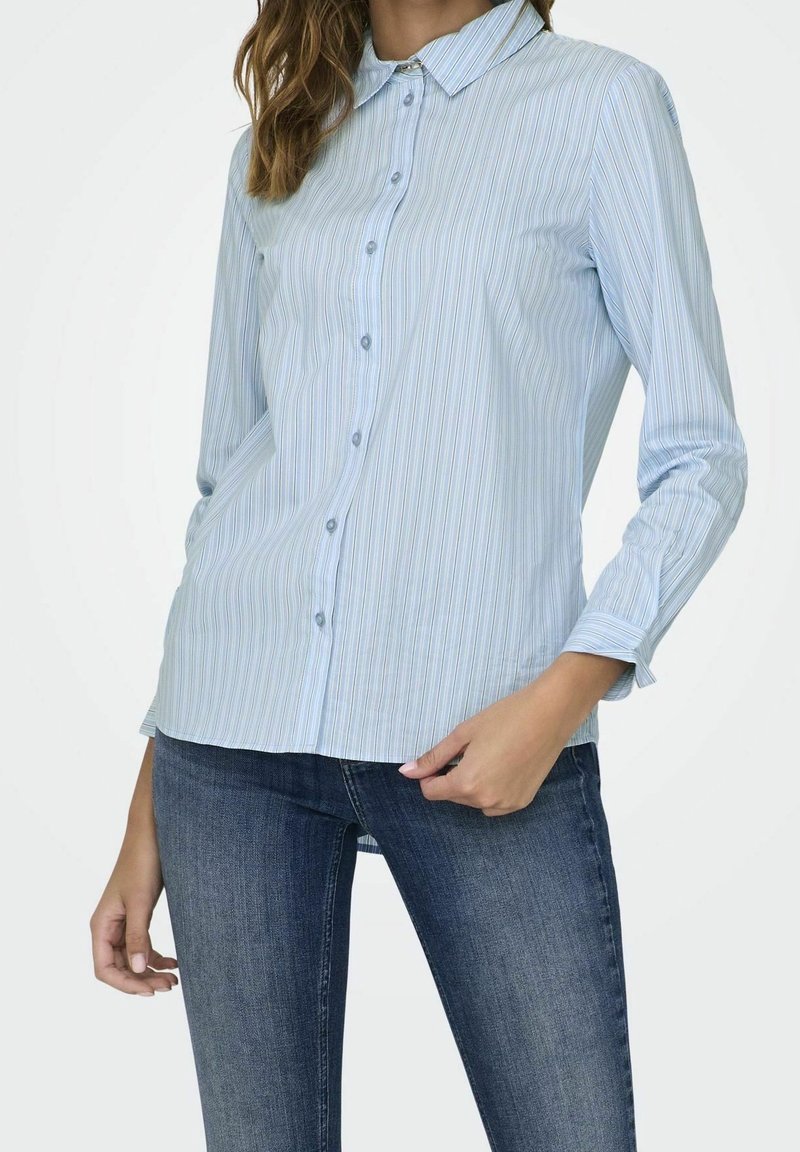 Light blue button-up shirt with vertical stripes, long sleeves, and a classic collar. Fabric appears smooth with a slightly fitted silhouette.