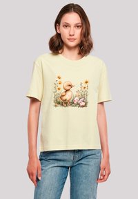 Yellow T-shirt featuring a printed illustration of a duckling among flowers and eggs. Short sleeves, round neck, and relaxed fit.