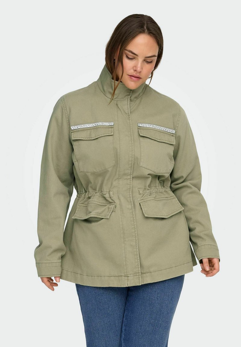 Olivgrüne Jacke mit hohem Kragen, verziert mit silbernen Pailletten auf den Brusttaschen und einem elastischen Bund für eine verstellbare Passform.