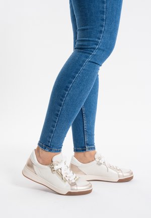 Baskets blanches et dorées métalliques avec une tige en cuir lisse, des lacets et une fermeture éclair sur le côté. Bout arrondi et semelle en caoutchouc durable.